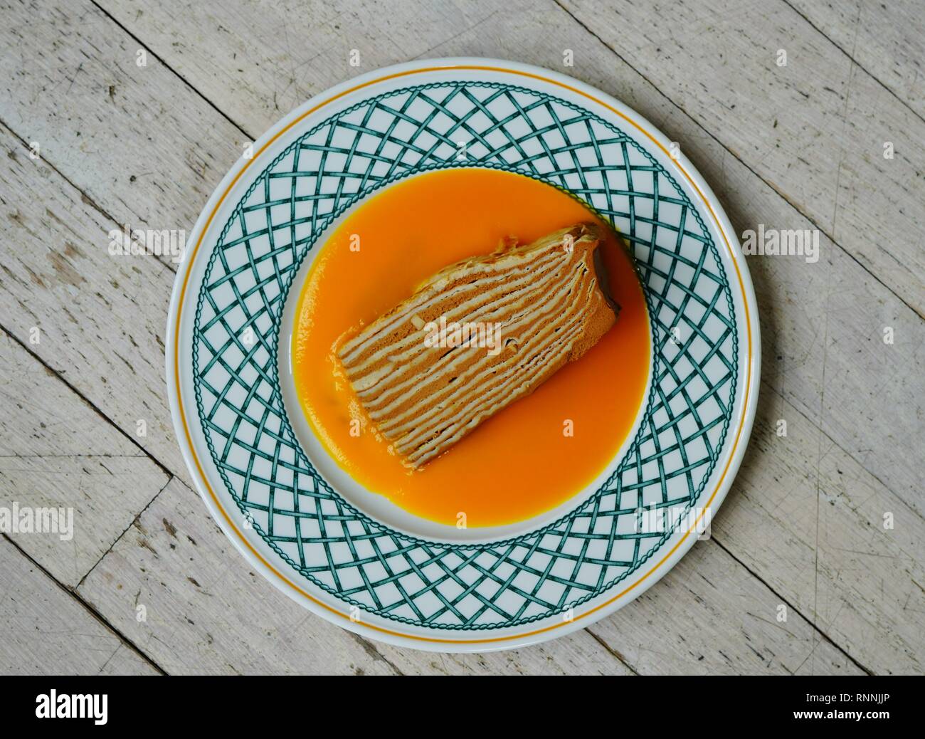 Tranche de gâteau vegan crêpe couche avec garniture au chocolat et coulis de mangue Banque D'Images