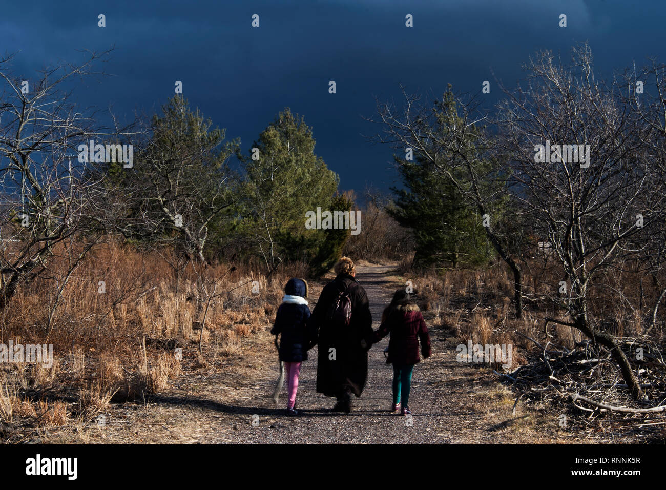 Enfants et adultes randonnée pédestre sentier wildlife refuge avec ciel sombre dramatique Banque D'Images