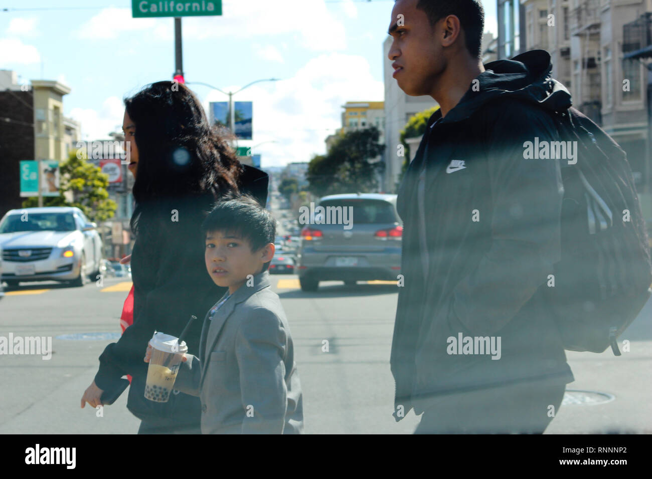Un jeune garçon se tourne vers la caméra en tant qu'il traverse la rue dans la ville de San Francisco, CA. Banque D'Images