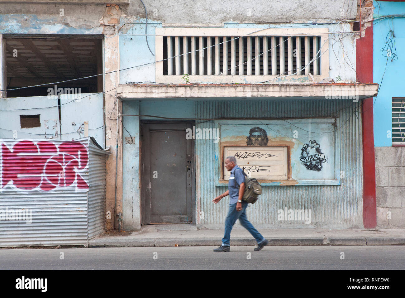 Homme marchant passé graffiti sur mur dans Havana street,Cuba Banque D'Images