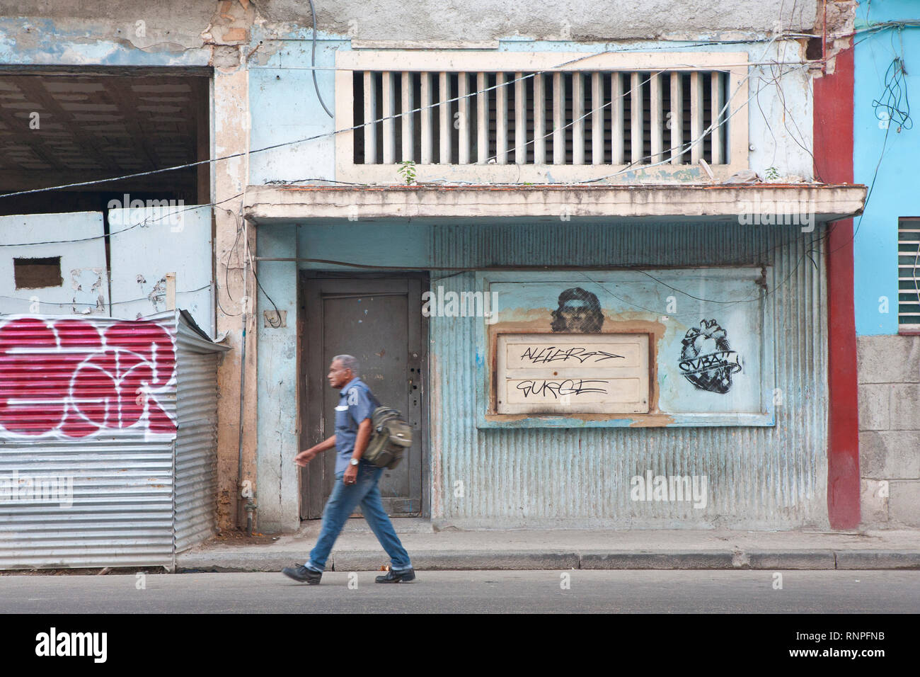 Homme marchant passé graffiti sur mur dans Havana street,Cuba Banque D'Images