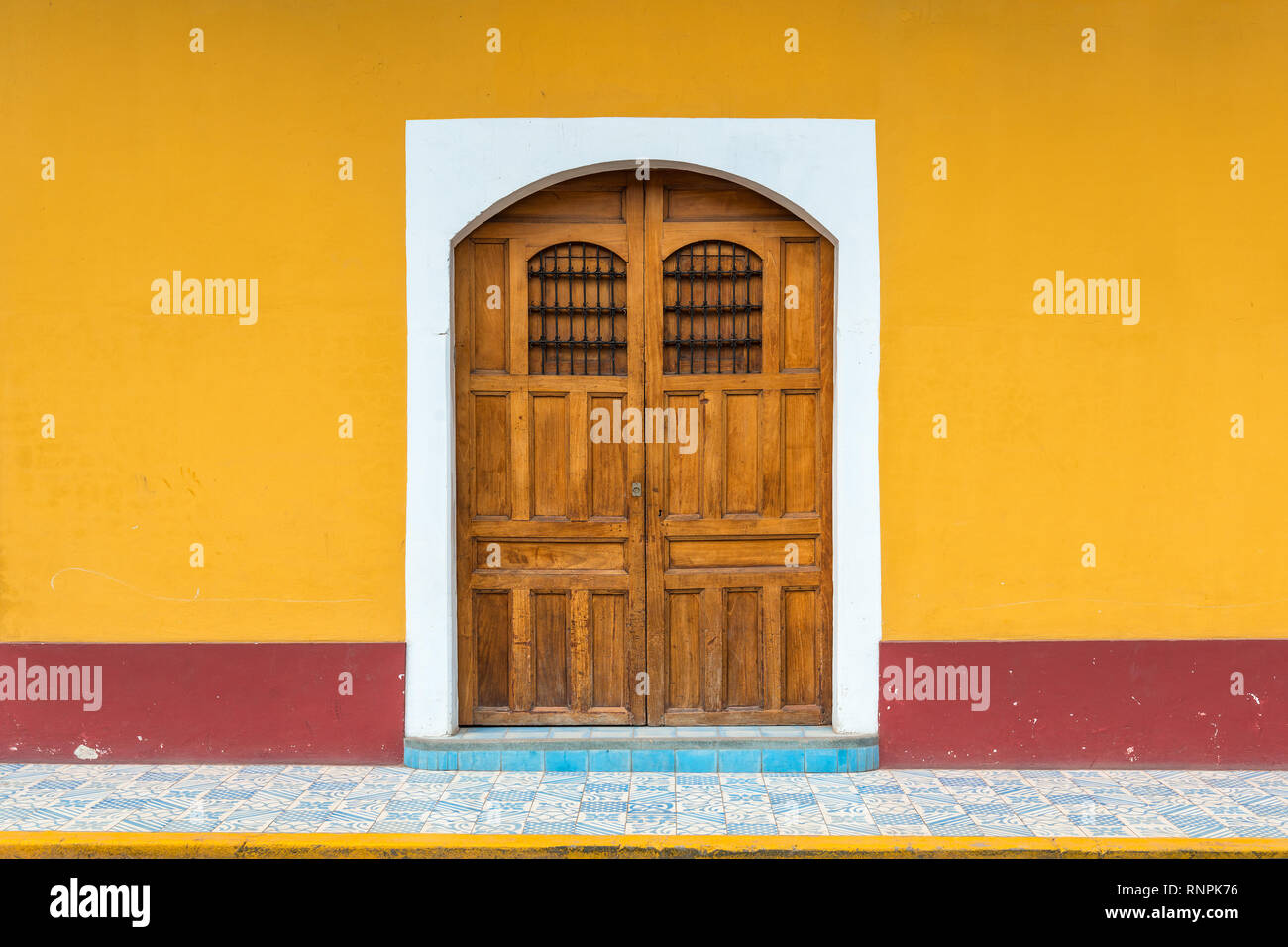 Façade d'une maison avec porte en bois et mur jaune dans le centre-ville historique de Grenade, au Nicaragua. Banque D'Images