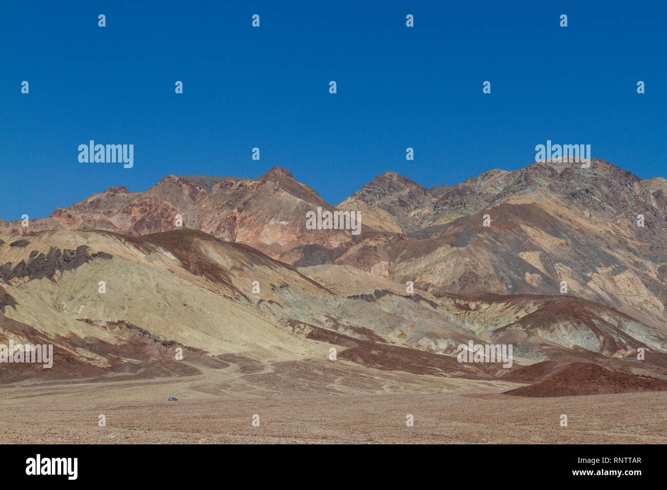 Une voiture (en bas à gauche du cadre) à l'approche de la palette de l'artiste domaine de la vallée de la mort, Death Valley National Park, California, United States. Banque D'Images