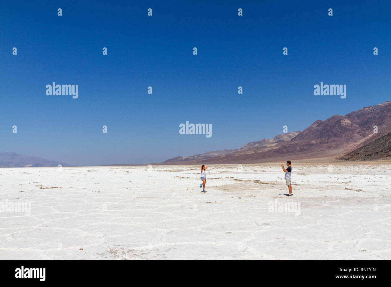 Un couple s'arrêter pour prendre une photo en marchant sur le marais salant, Badwater Basin, Death Valley National Park, California, United States. Banque D'Images