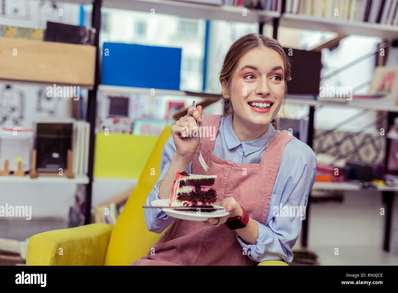 Impressionné fille positive d'être choqué avec goût de gâteau Banque D'Images