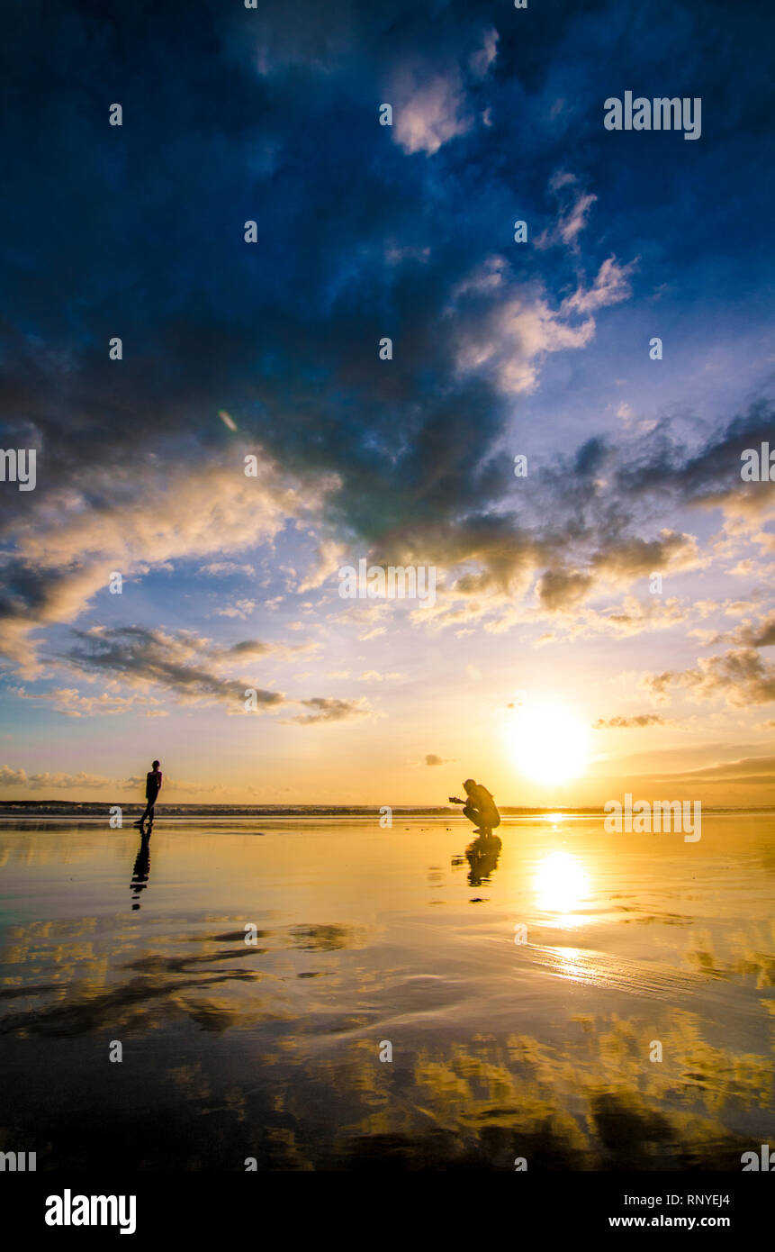 Deux peuples de prendre une photo alors que le coucher du soleil à double Six Beach, Legian, Kuta, Seminyak, Bali, Indonésie Banque D'Images