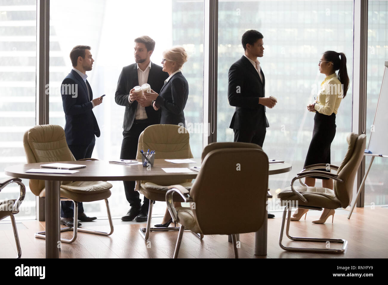 Divers groupes ethniques employés séparément debout à parler au travail pause Banque D'Images