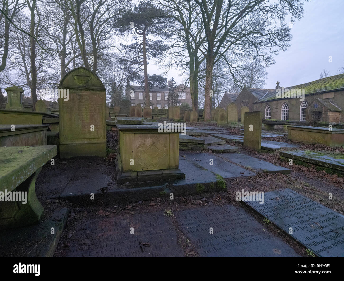 Église cimetière Haworth, West Yorkshire, avec le Bronte Parsonage Museum et old schoolhouse en arrière-plan, dans la brume matinale en hiver Banque D'Images