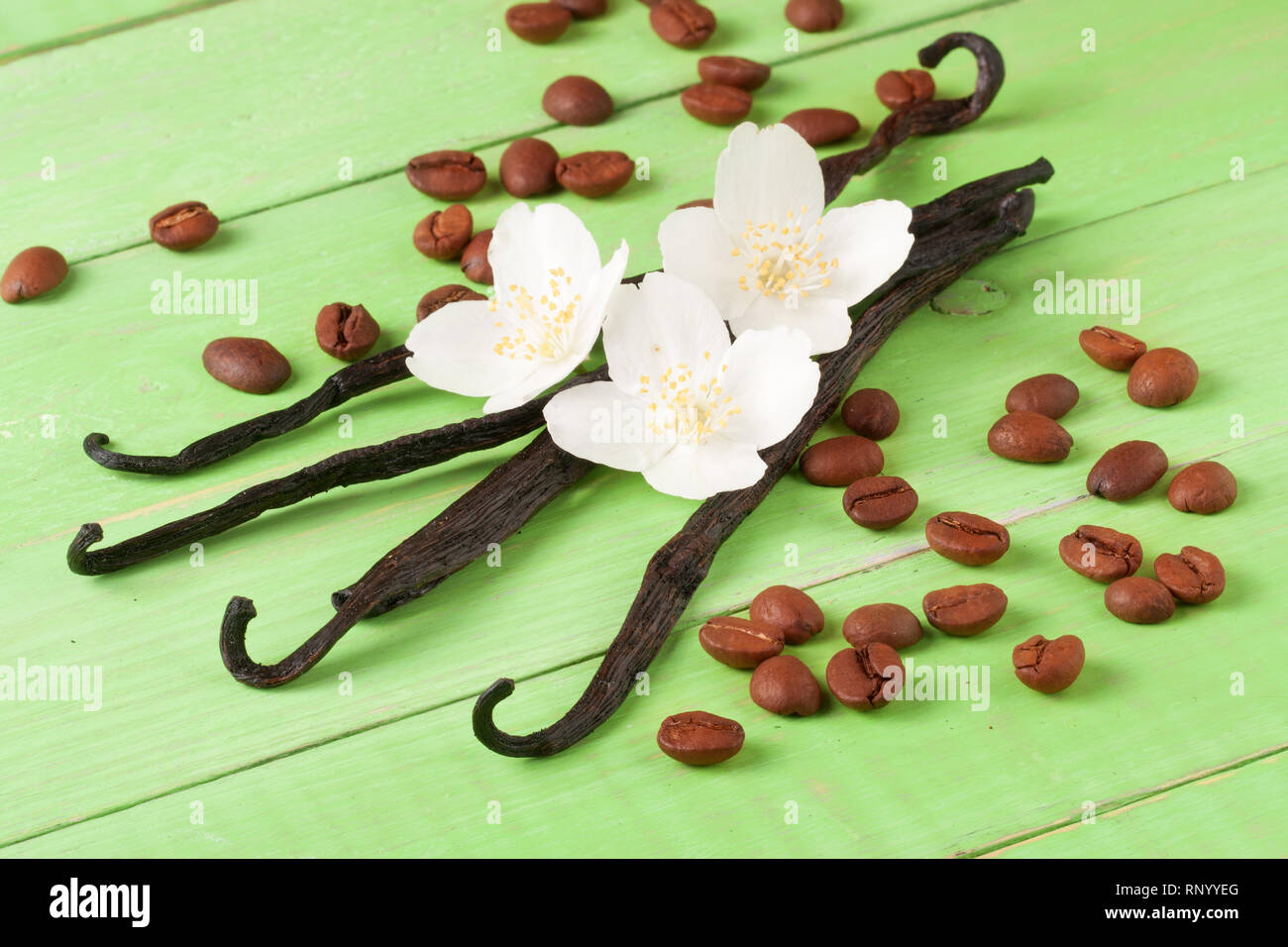 Bâtons de vanille et les grains de café avec fleur et feuille sur un fond de bois vert. Banque D'Images