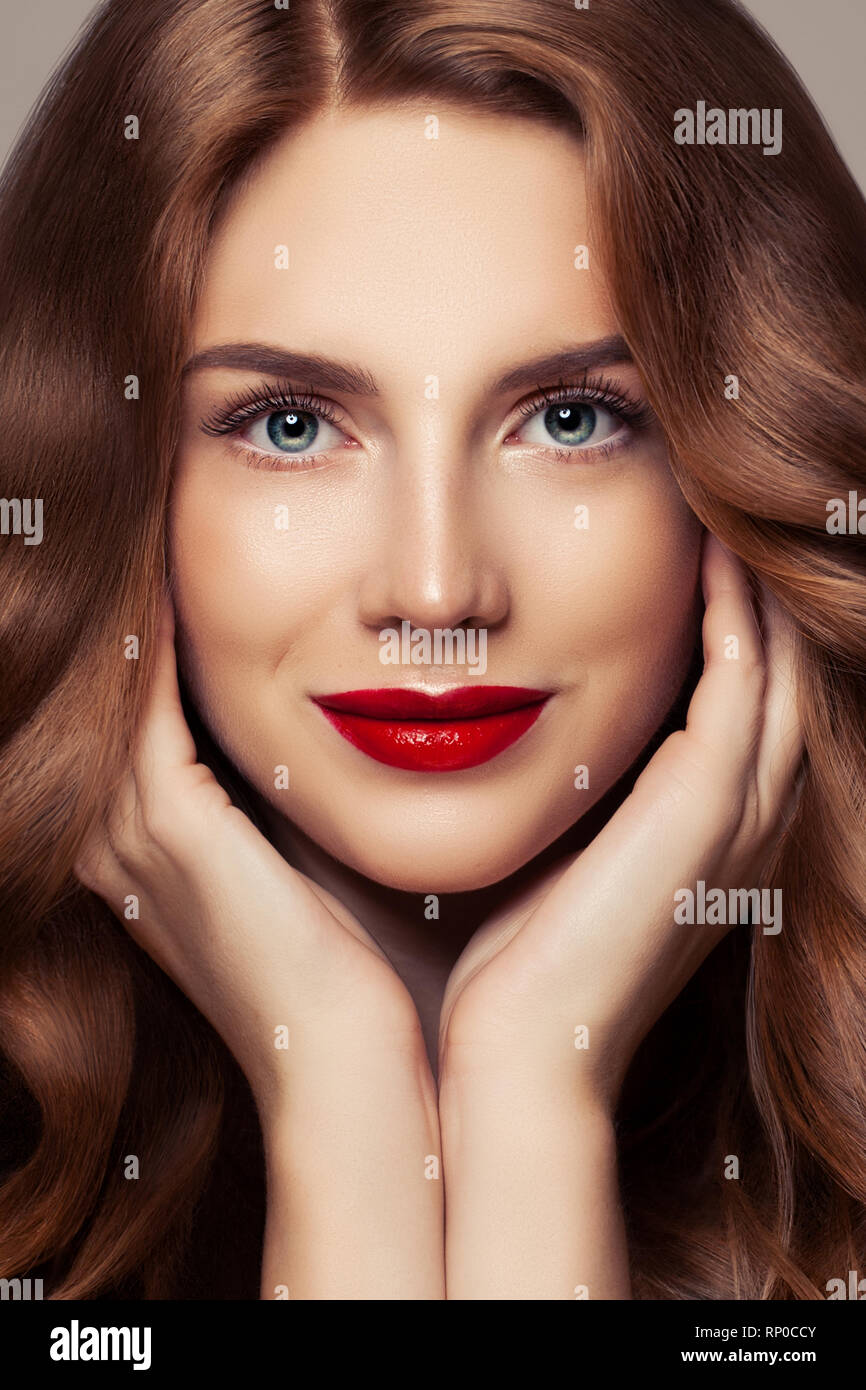 Visage de femme parfaite closeup portrait. Jolie femme avec des cheveux brillants et bouclés maquillage lèvres rouge Banque D'Images