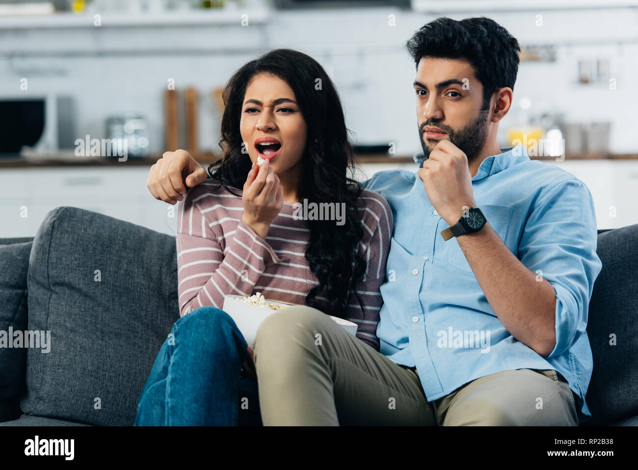 Couple de regarder la télévision en mangeant du maïs soufflé à la maison Banque D'Images