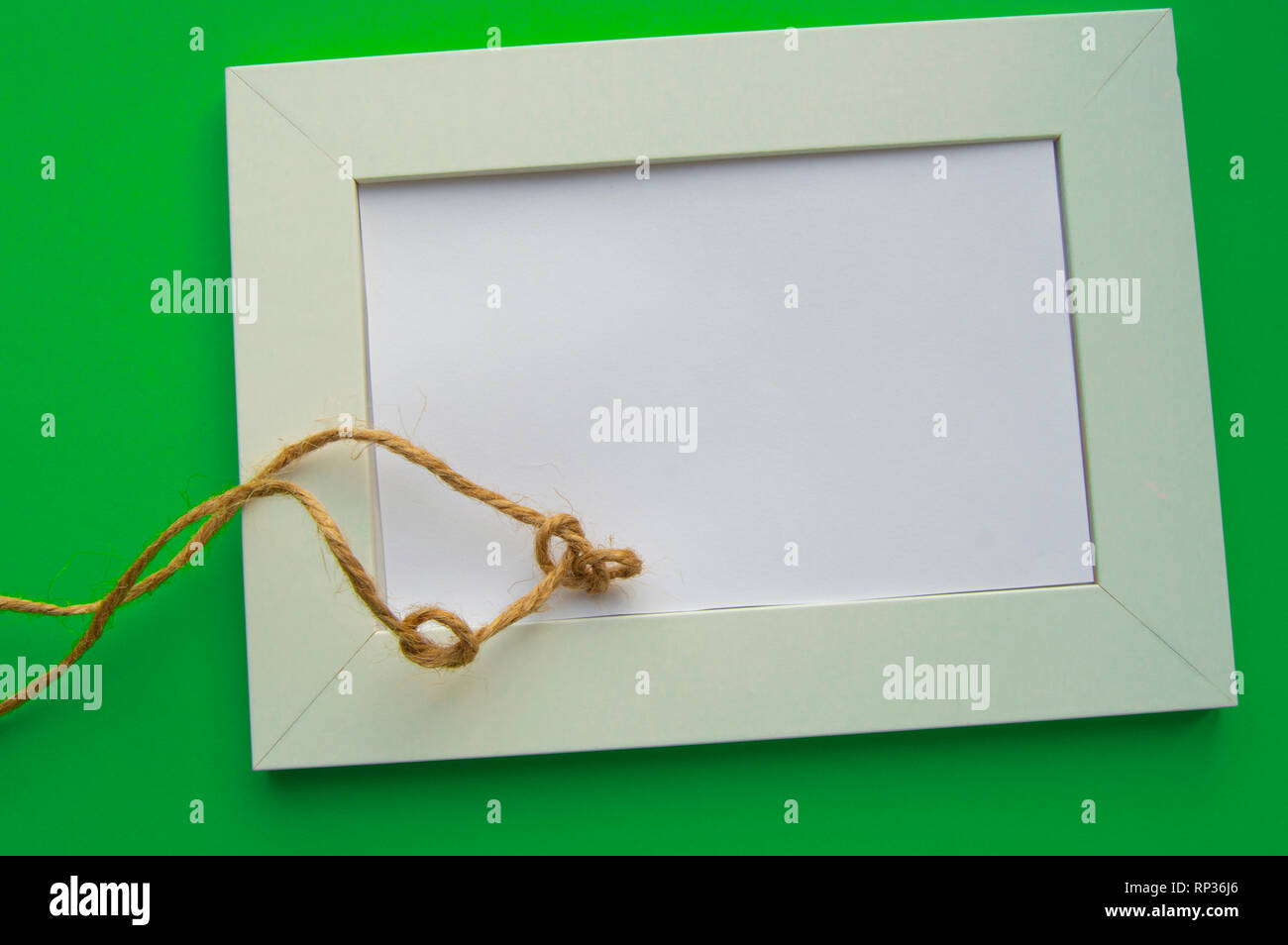 Cadre blanc vide avec espace pour texte se trouve sur un fond vert, décoré de noeuds en ficelle, pour célébrer la Saint-Patrick. Banque D'Images