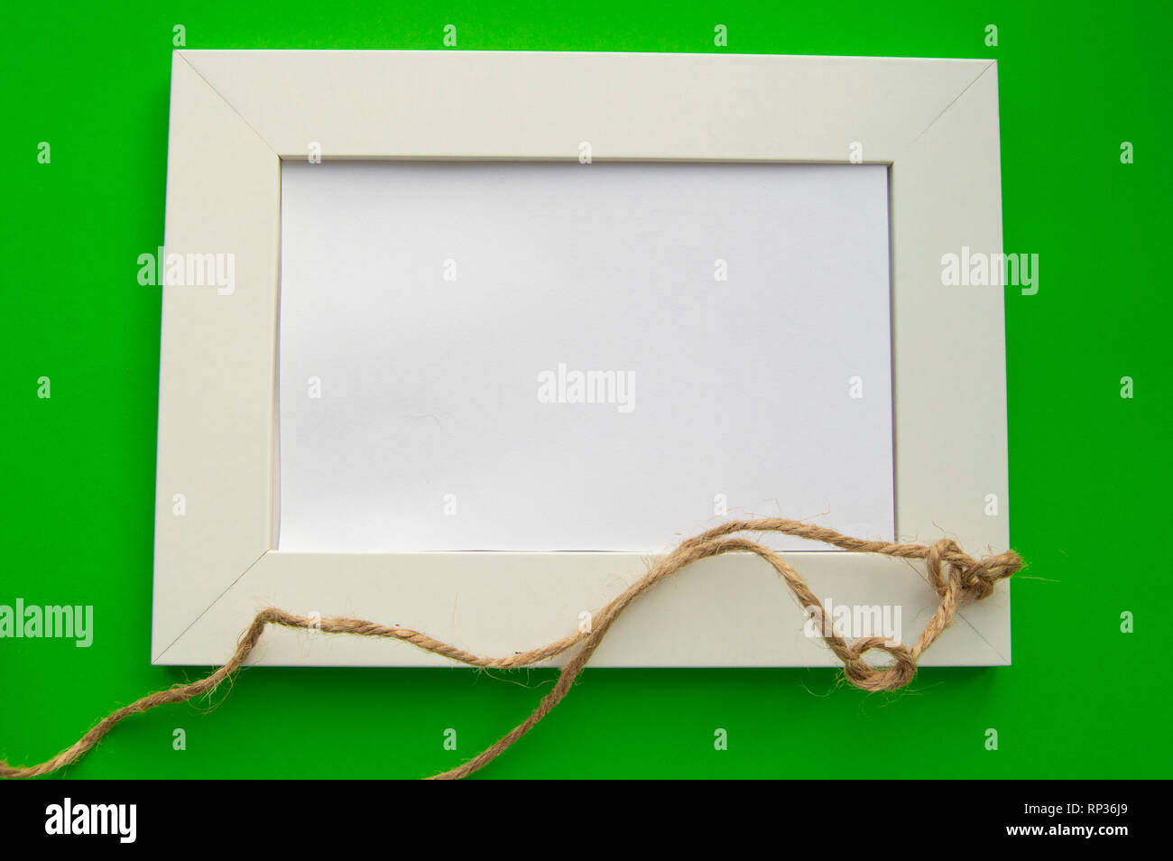 Cadre blanc vide avec espace pour texte se trouve sur un fond vert, décoré de noeuds en ficelle, pour célébrer la Saint-Patrick. Banque D'Images