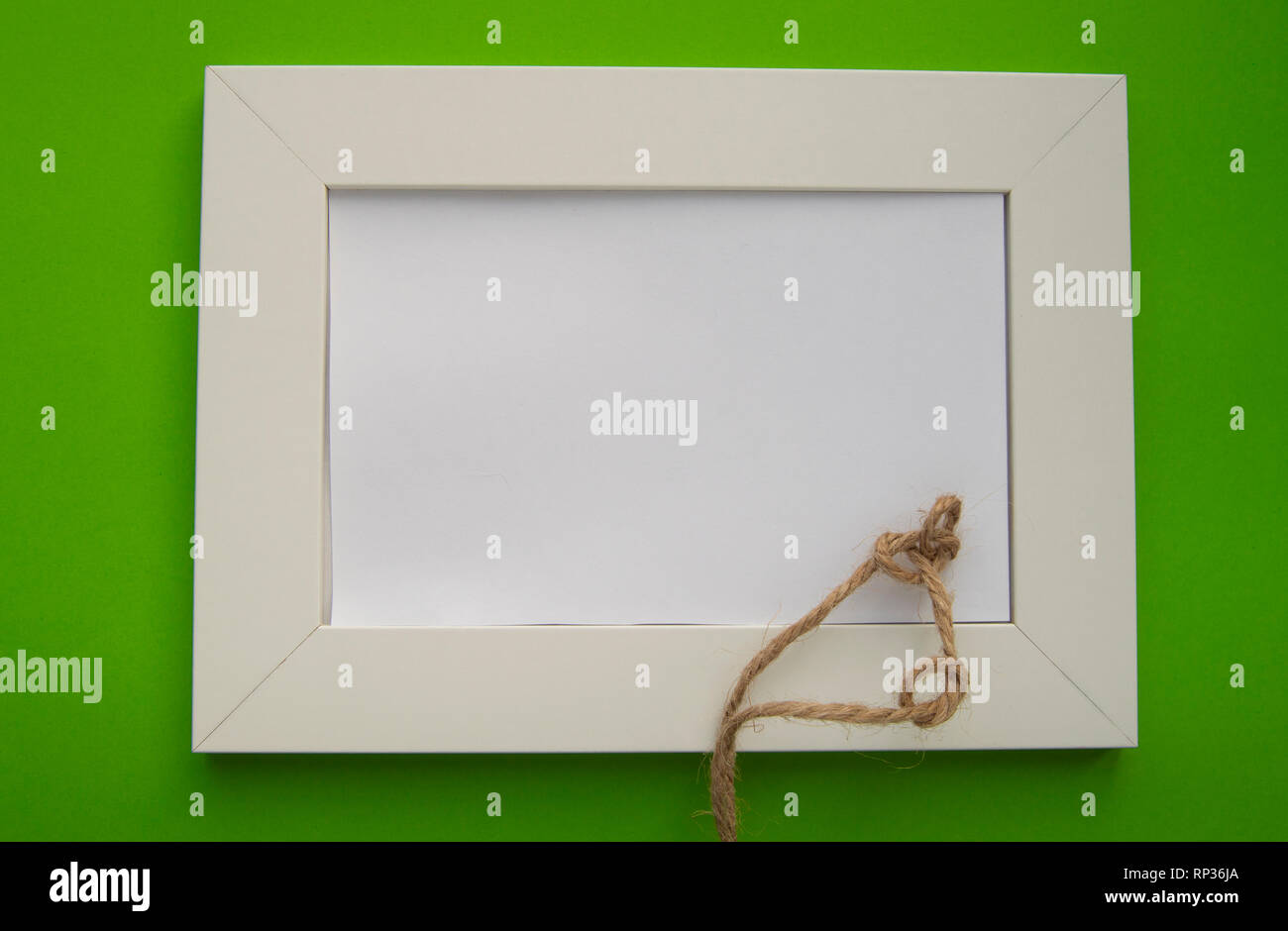 Cadre blanc vide avec espace pour texte se trouve sur un fond vert, décoré de noeuds en ficelle, pour célébrer la Saint-Patrick. Banque D'Images