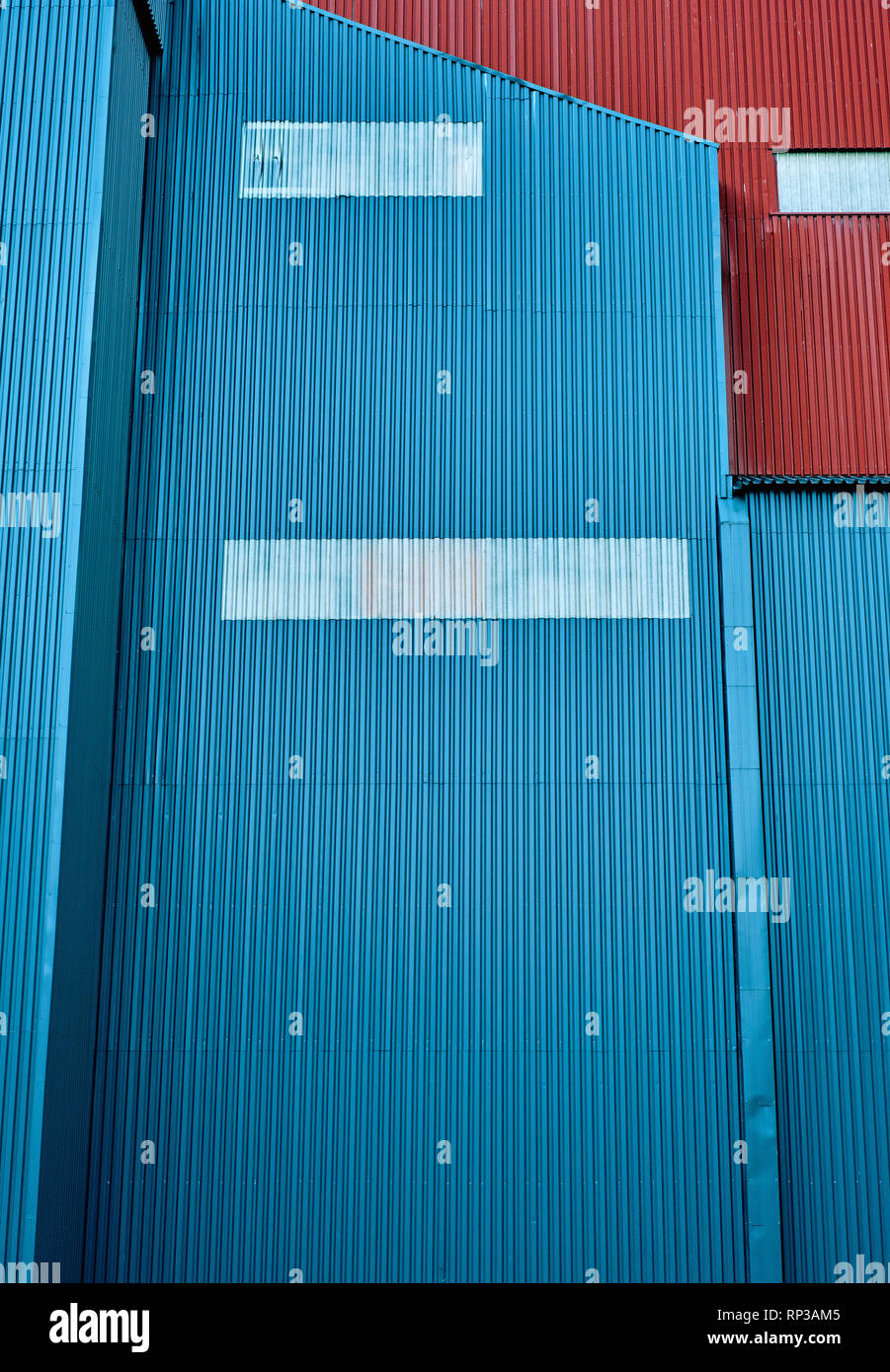 Bleu et rouge d'un revêtement métallique ondulé bâtiment industriel résumé détail. Banque D'Images