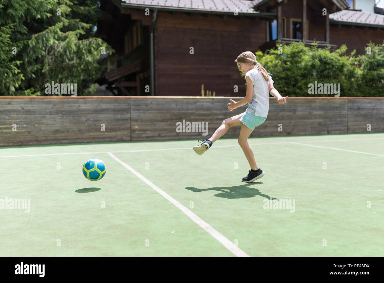 Une petite fille de 9 ans éduque sa technique de prise de vue avec un ballon de football sur le terrain de football Banque D'Images