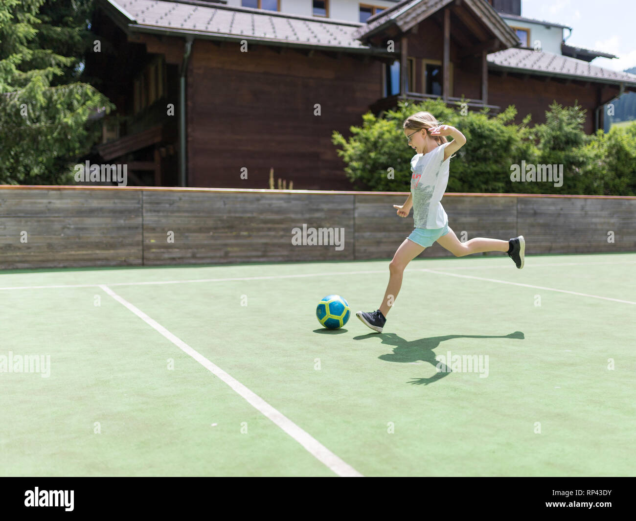 Une petite fille de 9 ans éduque sa technique de prise de vue avec un ballon de football sur le terrain de football Banque D'Images