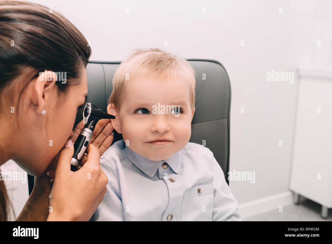 Petit garçon ayant l'examen de l'oreille avec un otoscope Banque D'Images