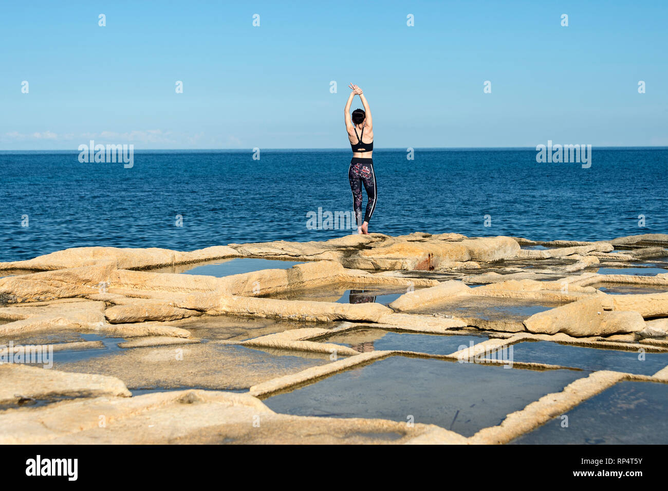 Vue arrière d'un côté une femme étirements en dehors par la mer le port d'un soutien-gorge de sport et leggings Banque D'Images