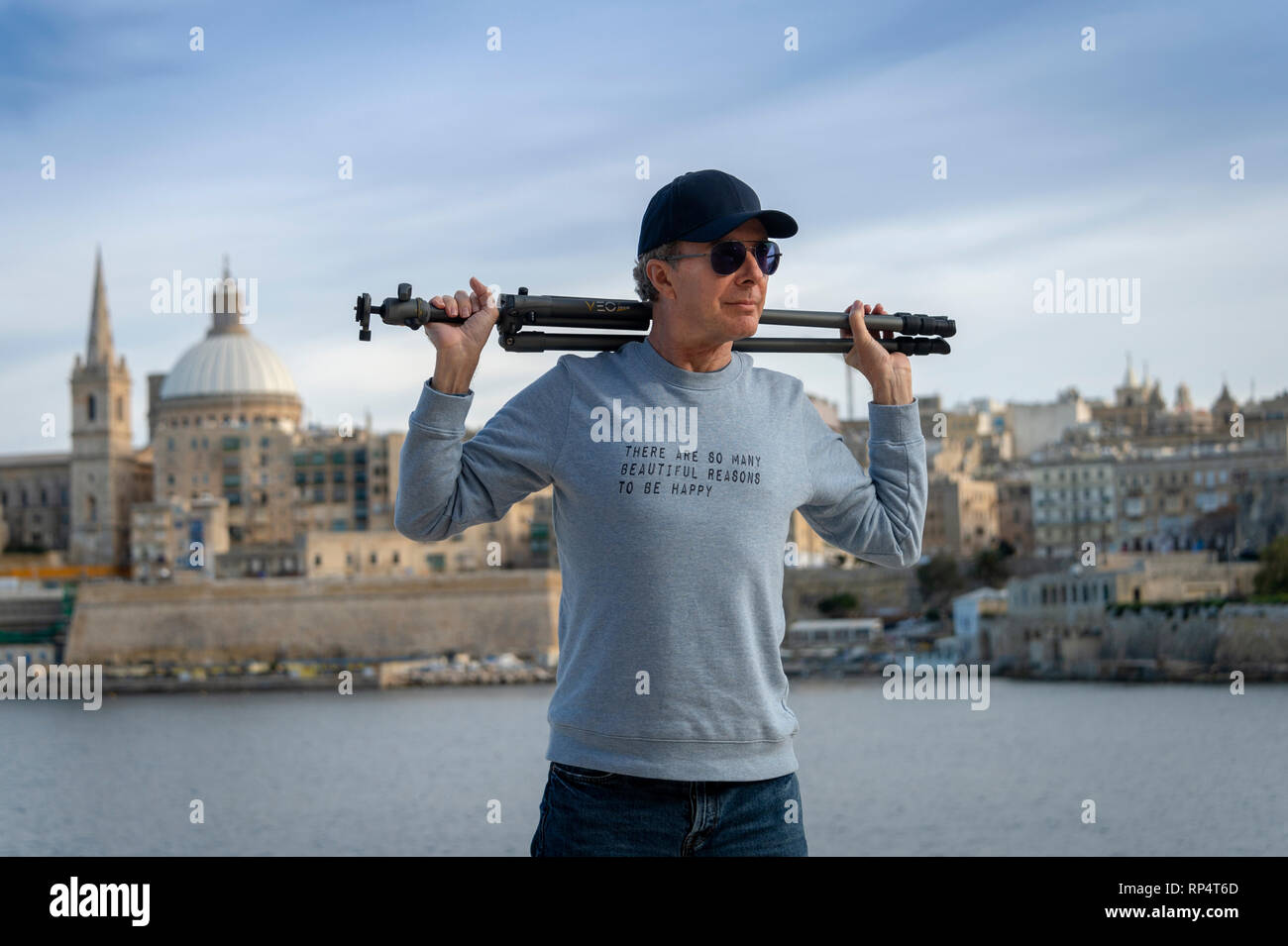 Homme portant un trépied photographique avec La Valette, Malte dans l'arrière-plan portant un sweat-shirt avec le slogan "Il y a tellement de belles raisons de Banque D'Images