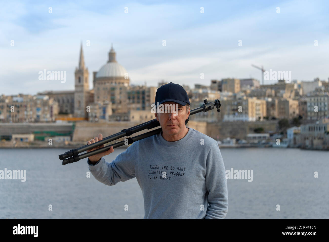 Homme portant un trépied photographique avec La Valette, Malte dans l'arrière-plan portant un sweat-shirt avec le slogan "Il y a tellement de belles raisons de Banque D'Images