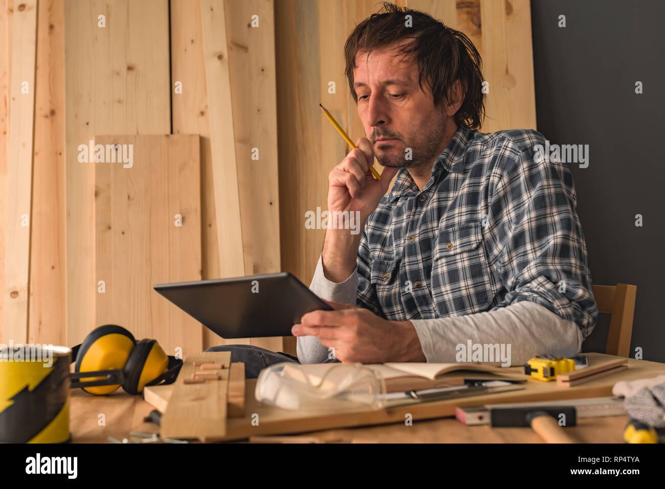 Carpenter using digital tablet in small business atelier de menuiserie pour la planification d'un nouveau projet de bricolage Banque D'Images