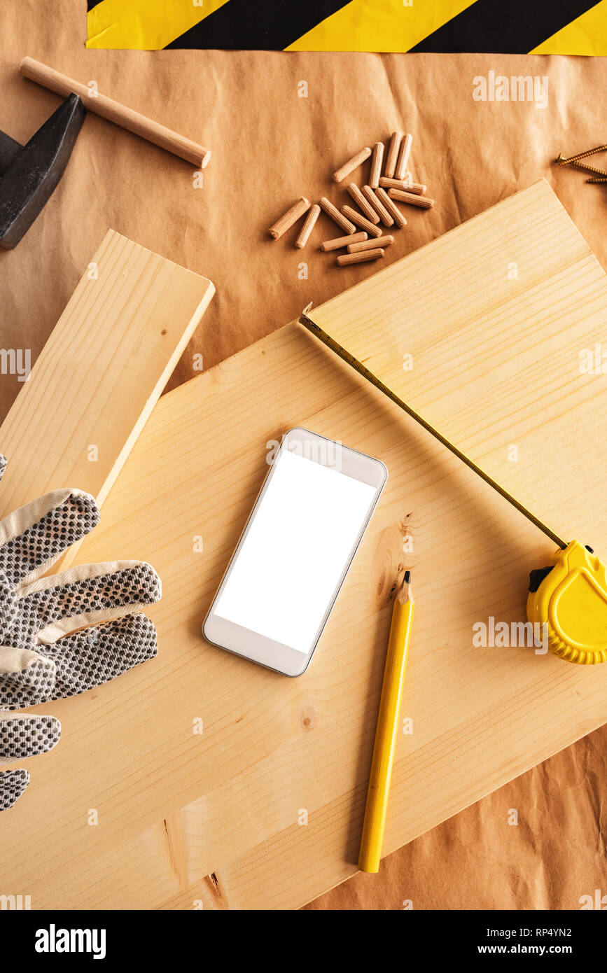 Smartphone moderne blanc avec écran vide maquette dans la petite entreprise de menuiserie atelier de menuiserie, vue du dessus Banque D'Images