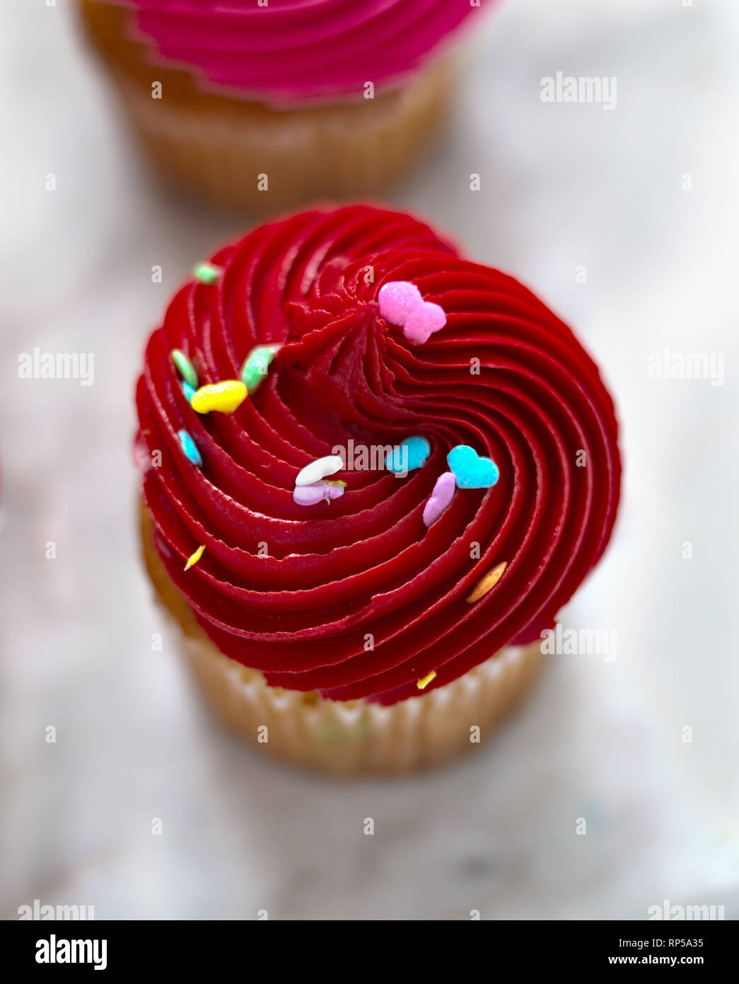 Cupcake vanille avec glaçage rouge et coeur arrosés. Cupcake sur un plateau en marbre. Banque D'Images