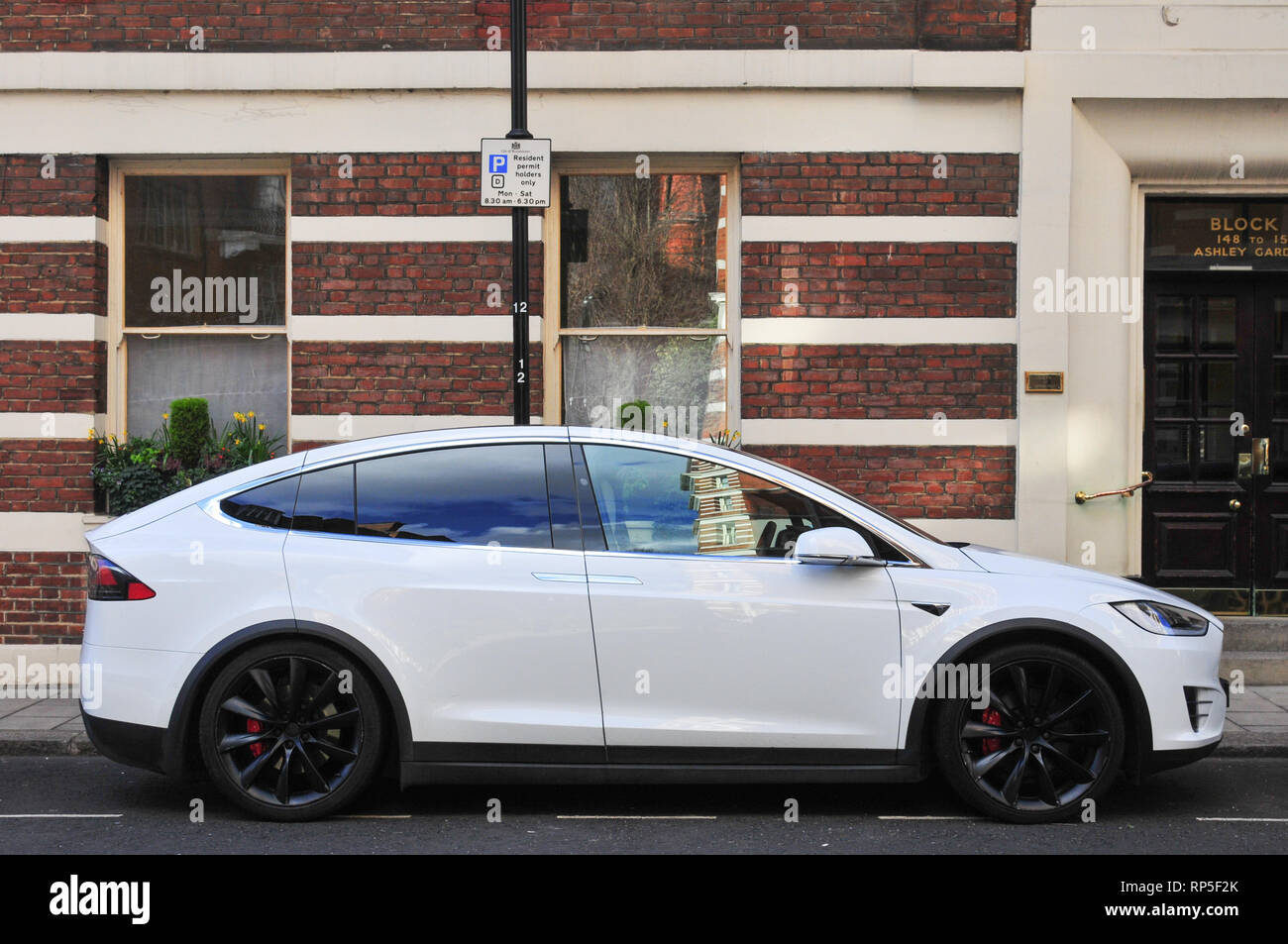 Un livre blanc voiture électrique Tesla Model X avec roues Noire stationnée sur une rue de Londres avec un bâtiment en brique à l'arrière-plan. Banque D'Images