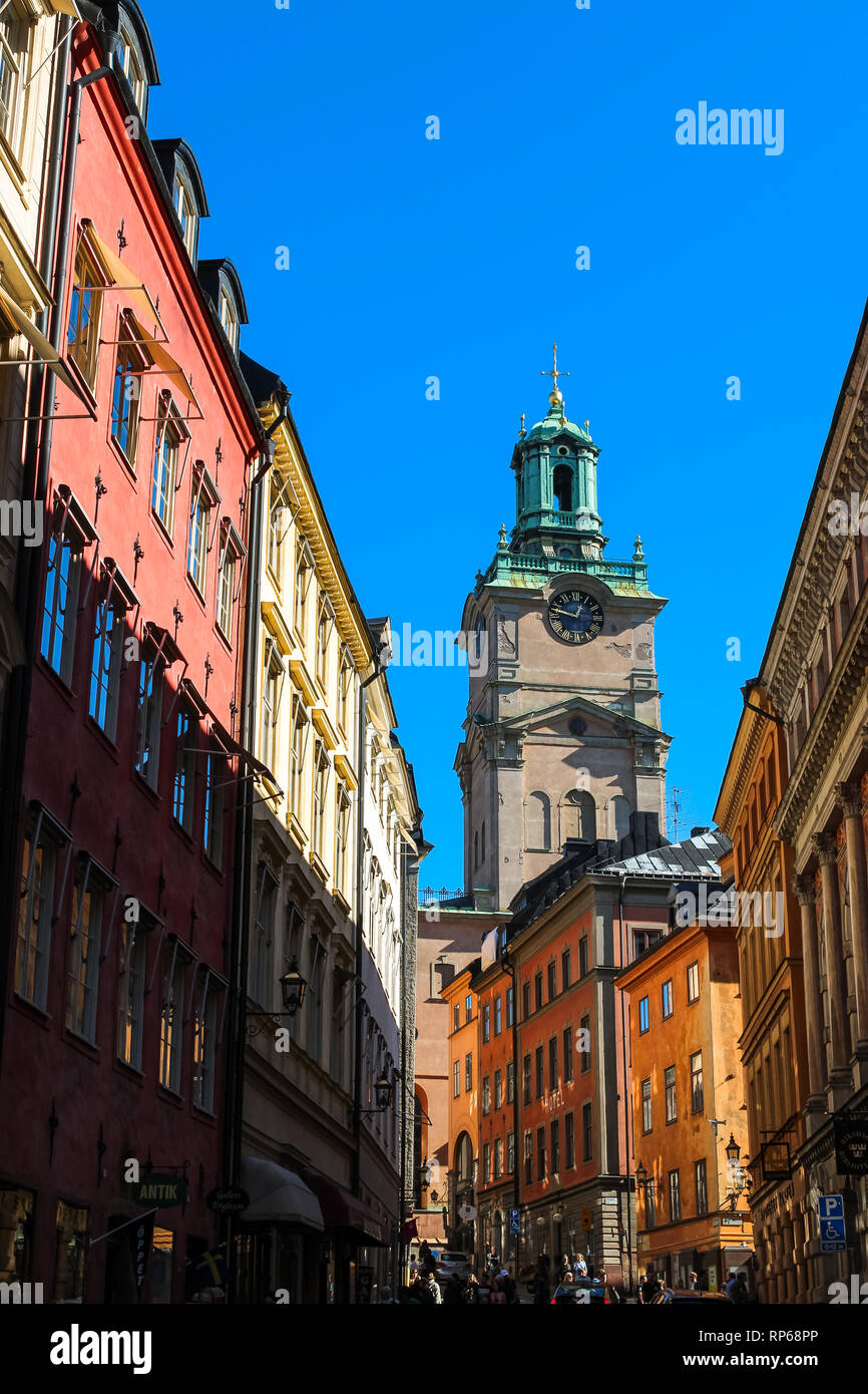 Vue sur Sankt Nikolai kyrka à Stockholm par une allée suédois typique avec ses maisons colorées et ciel bleu sans nuage (Stockholm, Suède, Europe) Banque D'Images
