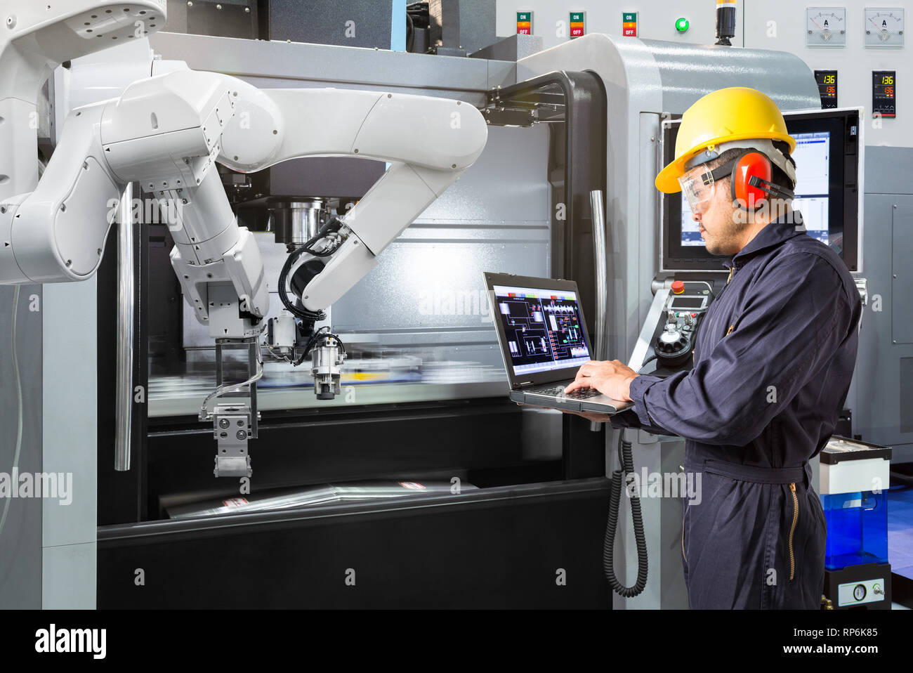 Ingénieur de maintenance en utilisant un ordinateur portable contrôle automatique main robotique avec machine CNC dans smart factory. 4.0 Concept de l'industrie Banque D'Images