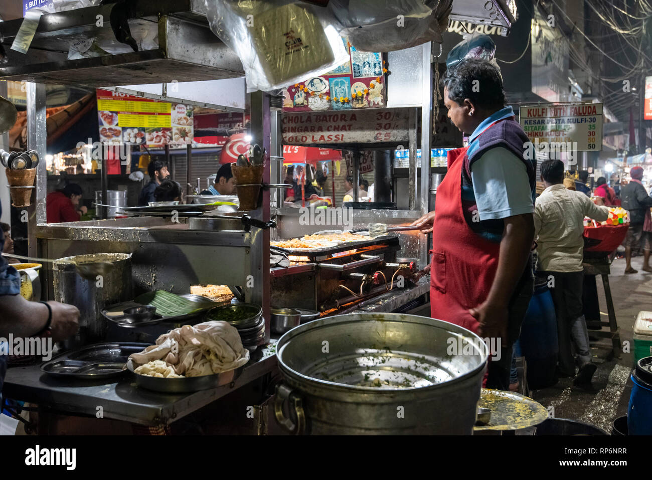 L'atmosphère typique occupé nuit bruyante scène de rue à Calcutta avec un fournisseur d'aliments de rue faisant un Paratha Placez Mughlai Bengali populaire street food. Banque D'Images