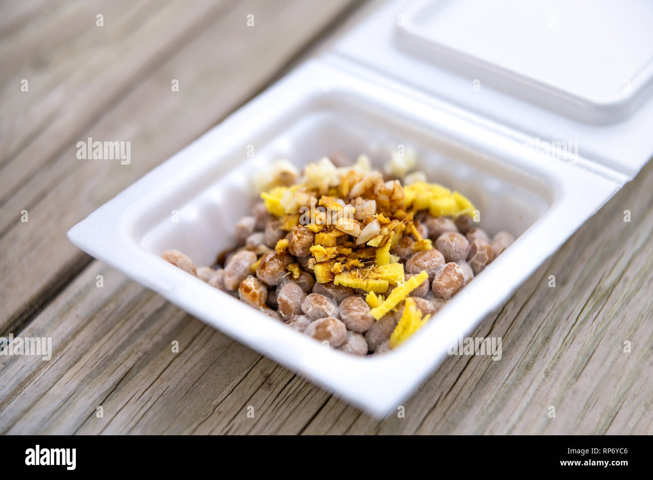 Le natto japonais asiatique plat de soja fermenté gros plan de repas dans un récipient Japon fort et garnitures sauce soja ail et le gingembre sur macro table en bois Banque D'Images