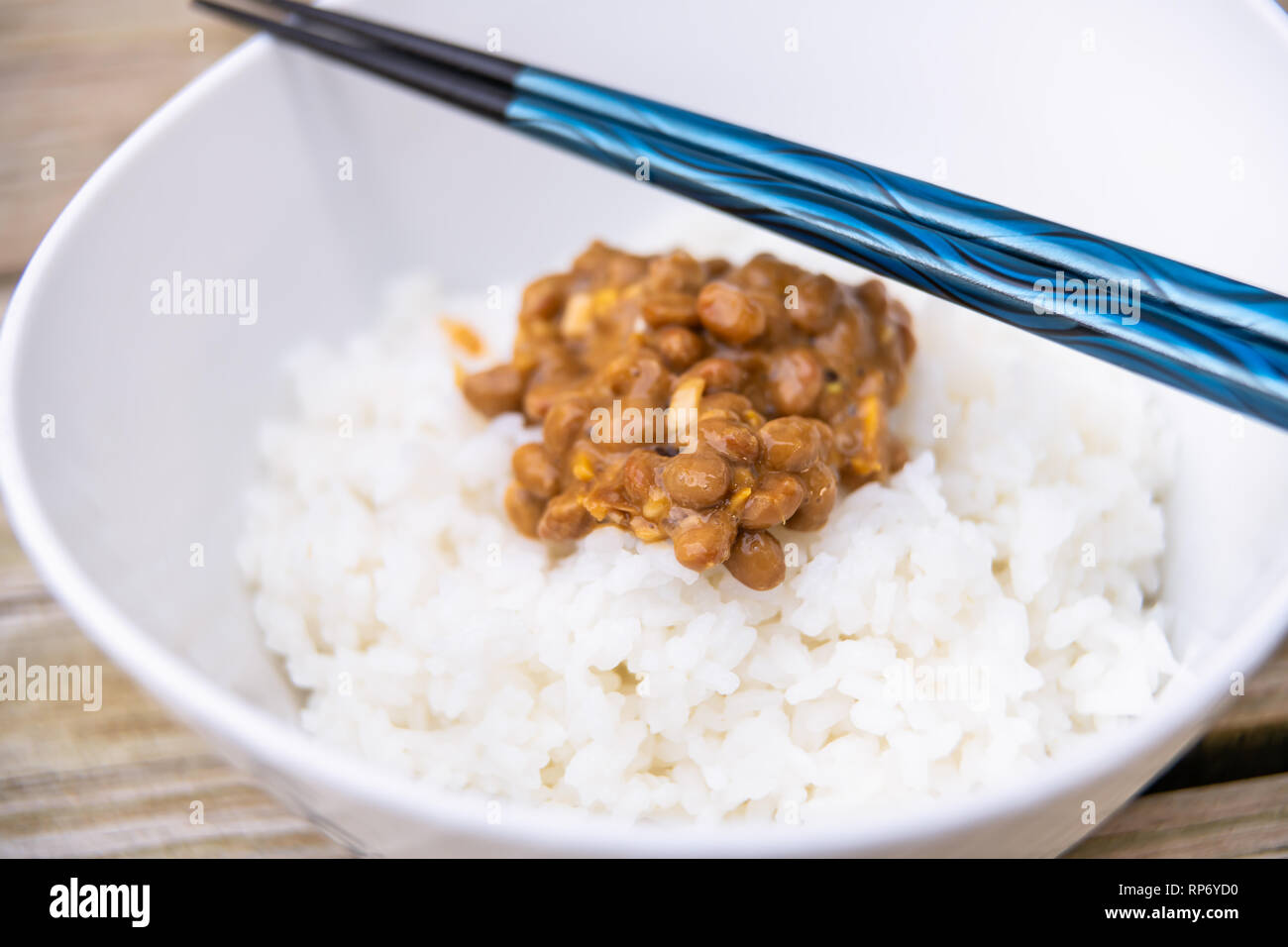 Libre de baguettes bleu sur le natto japonais asiatique plat de soja fermenté en texture visqueuse collante de repas blanc ordinaire dans un bol de riz cuit à la vapeur Banque D'Images