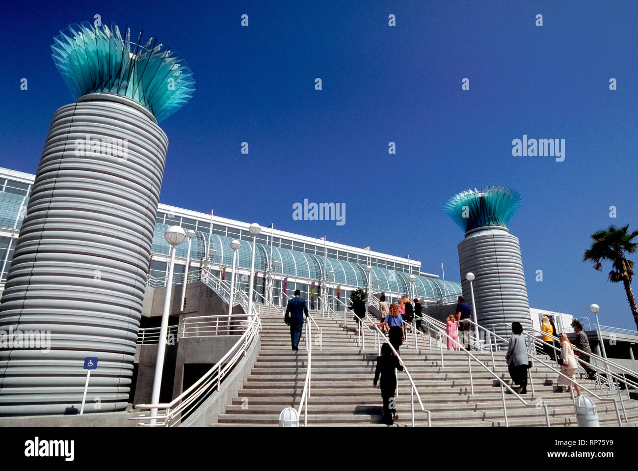 Les participants via ascend large pas passé une paire de colonnes en verre contemporain d'entrer dans le centre de congrès de Long Beach qui est situé le long du secteur riverain du centre-ville de Long Beach, Californie, USA. L'impressionnante façade de verre du bâtiment vous permet de beaucoup de soleil dans les salles d'exposition et des salles de réunion qui font partie d'une convention et d'un complexe de divertissement comprend également deux théâtres et une arène pour des concerts et des événements sportifs. Banque D'Images