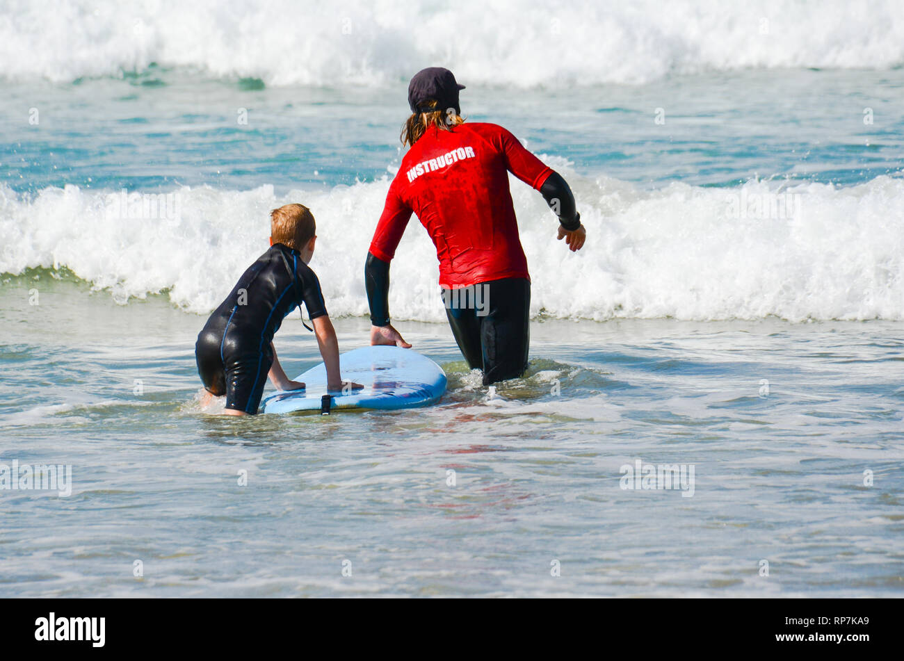 Jeune garçon surfe entre adultes avec instructeur pendant les débutants leçon de surf. Comme d'enfant bénéficie d'un mode de vie sain active par apprendre à surfer. Banque D'Images