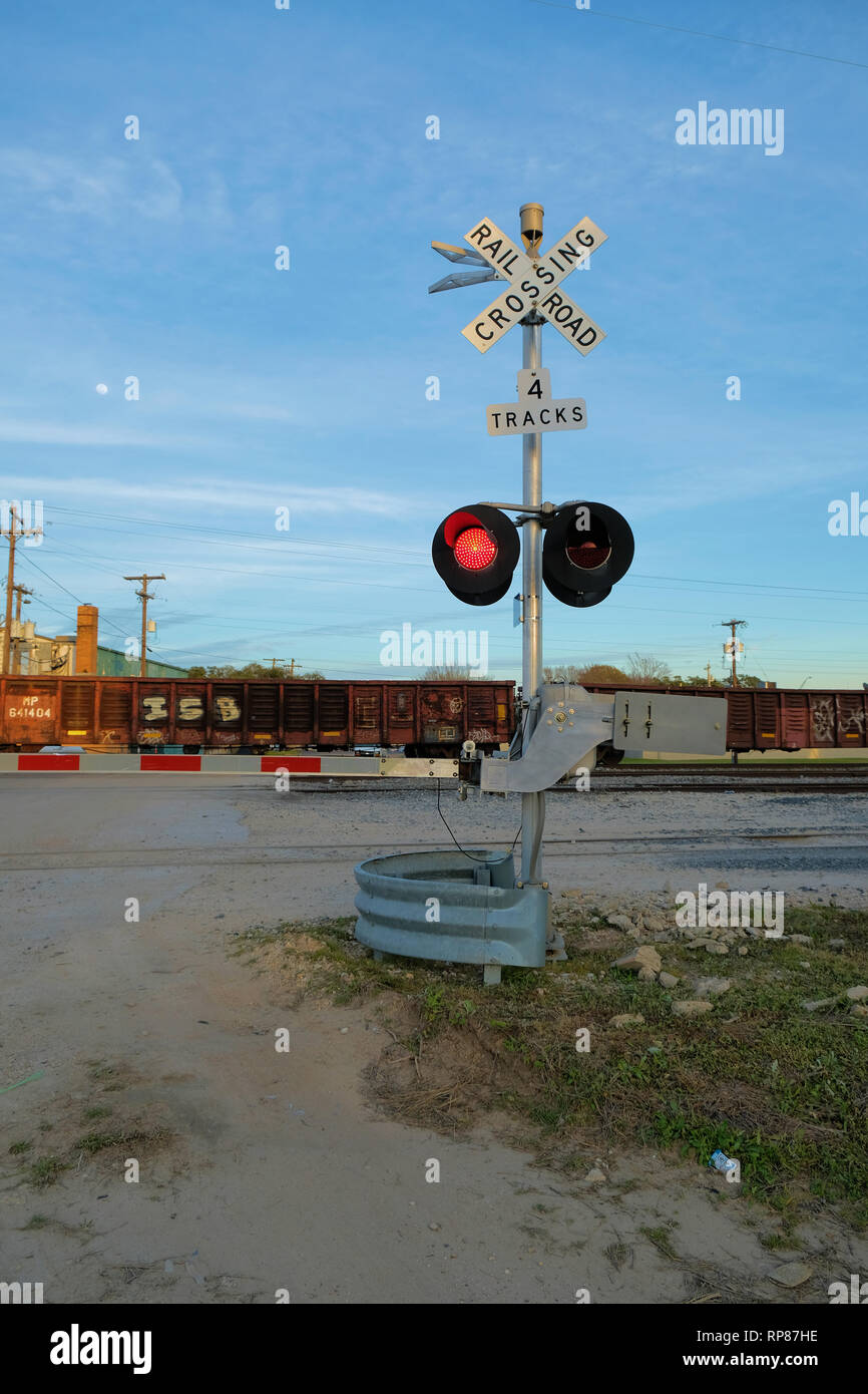 La rampe de fer à un niveau barrière de passage à niveau avec un train passant par en arrière-plan ; quatre passages à niveau de la voie ; Bryan, Texas, USA. Banque D'Images