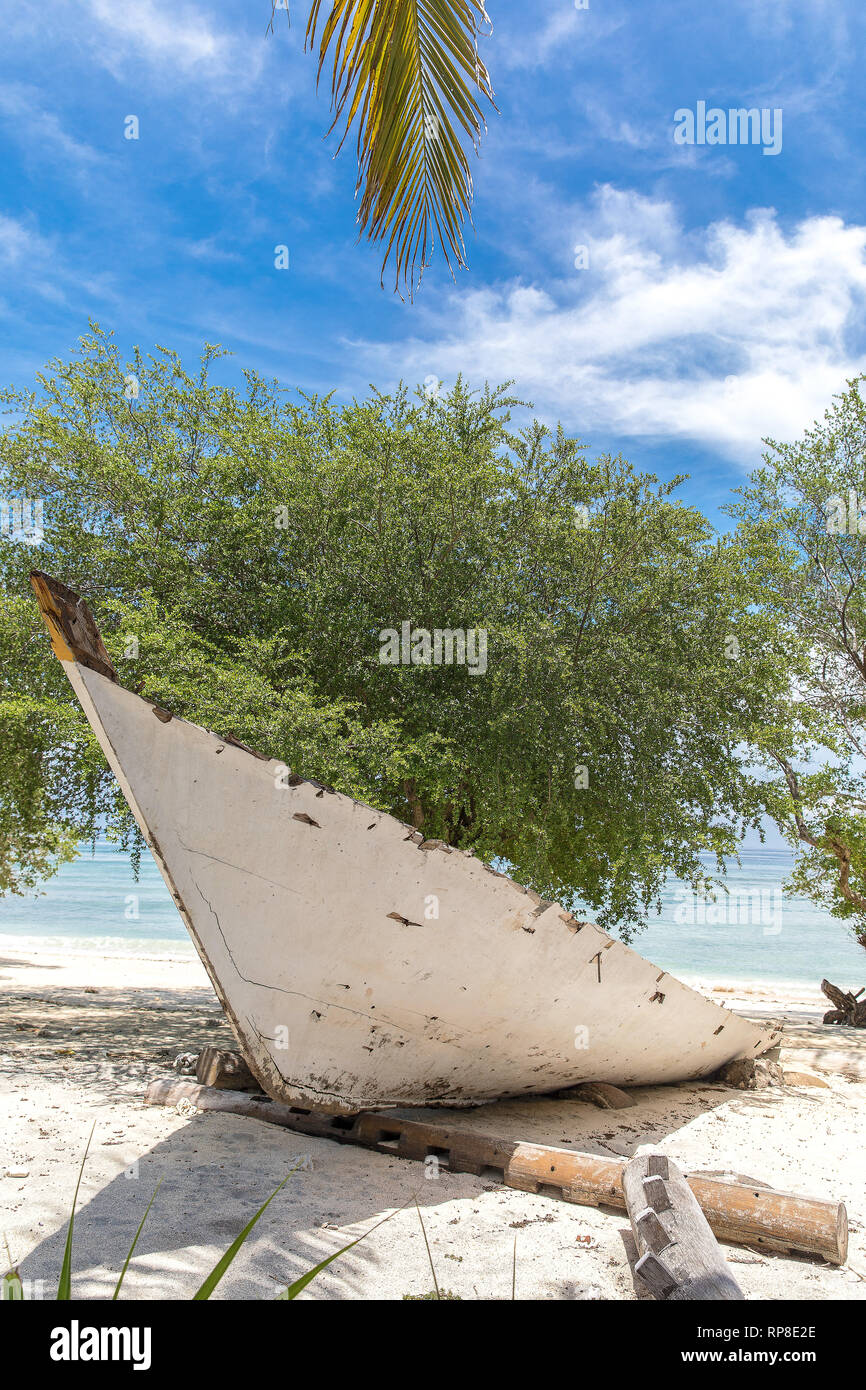 L'Indonésie, l'ancien bateau blanc sur le front de mer sur l'île de Gili Trawangan et le dragon-comme l'arbre. Banque D'Images