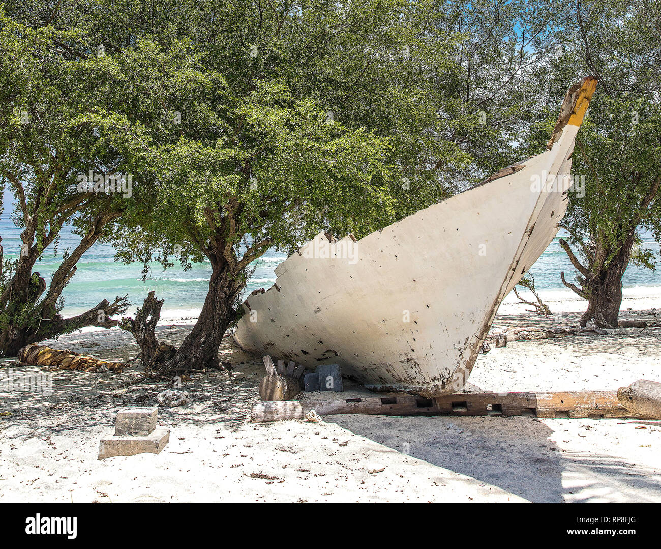 L'Indonésie, l'ancien bateau blanc sur le front de mer sur l'île de Gili Trawangan et le dragon-comme l'arbre. Banque D'Images