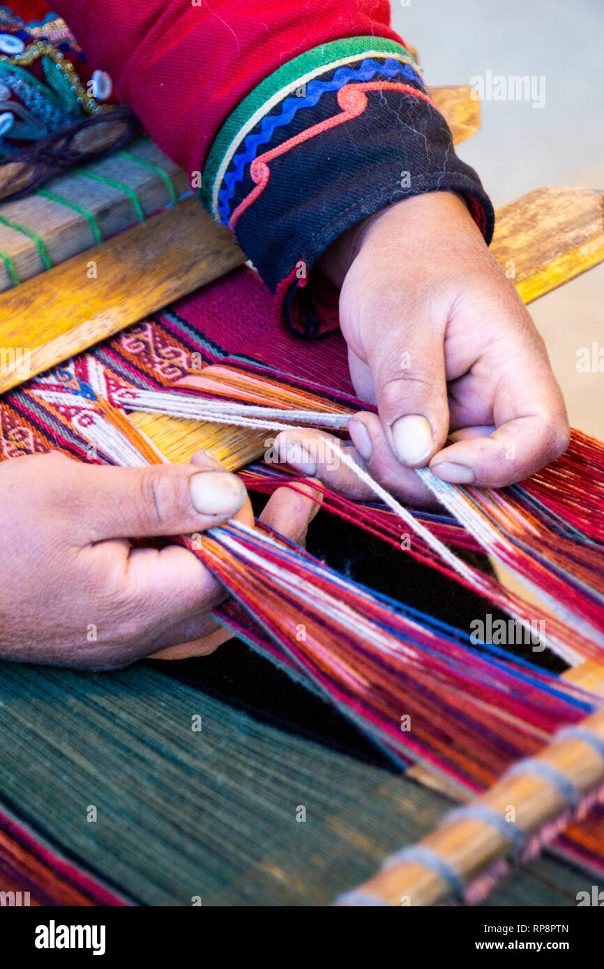 Femme en costume traditionnel tisse des fils d'alpaga à Vallée sacrée, région de Cuzco, Pérou. Banque D'Images