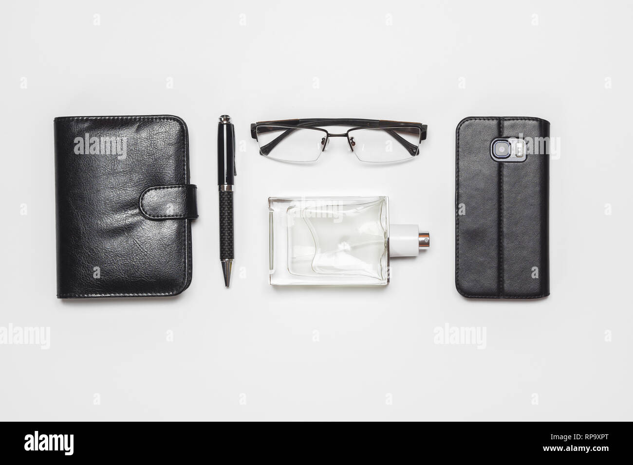 Télévision jeter dessus messieurs's accessoires sur fond blanc. Les lunettes, parfums, smartphone, stylo, bloc-notes de journal sur fond blanc. Banque D'Images