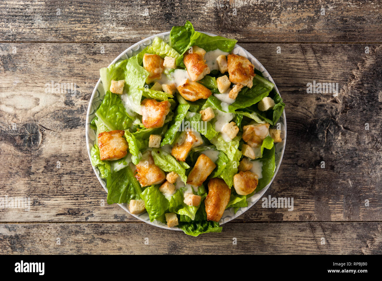 Caesar salade de laitue, poulet et de croûtons sur table en bois. Vue d'en haut. Banque D'Images