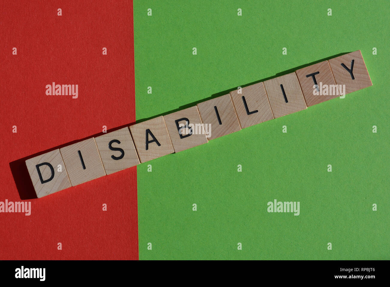 Concept créatif : le handicap dans les lettres en bois, dis sur le rouge et capacité sur fond vert, Banque D'Images