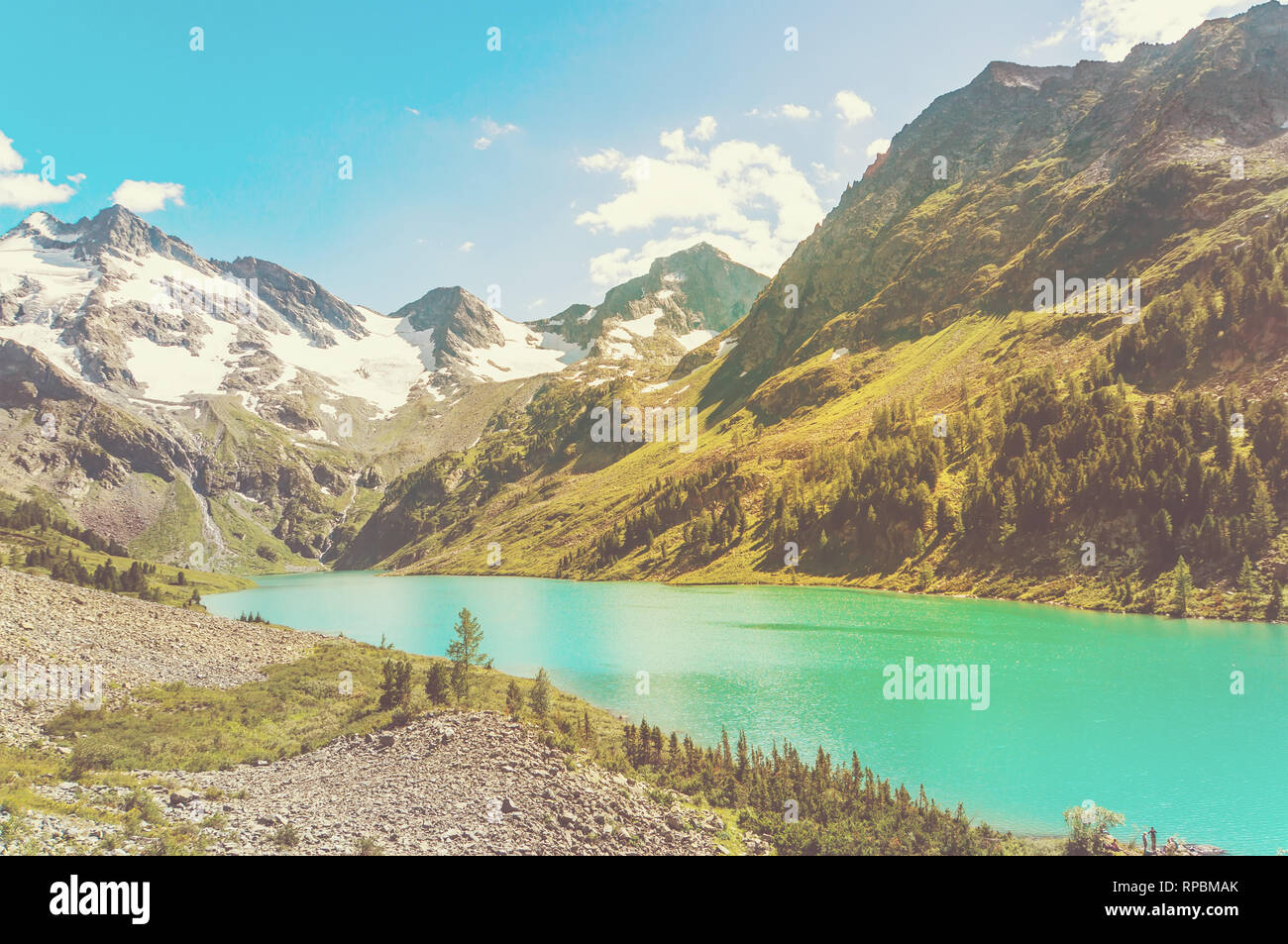 Lac de montagne, la Russie Sibérie Altaï. Belle pente de montagne parsemée de rochers sur la toile de fond de belles collines enneigées Banque D'Images