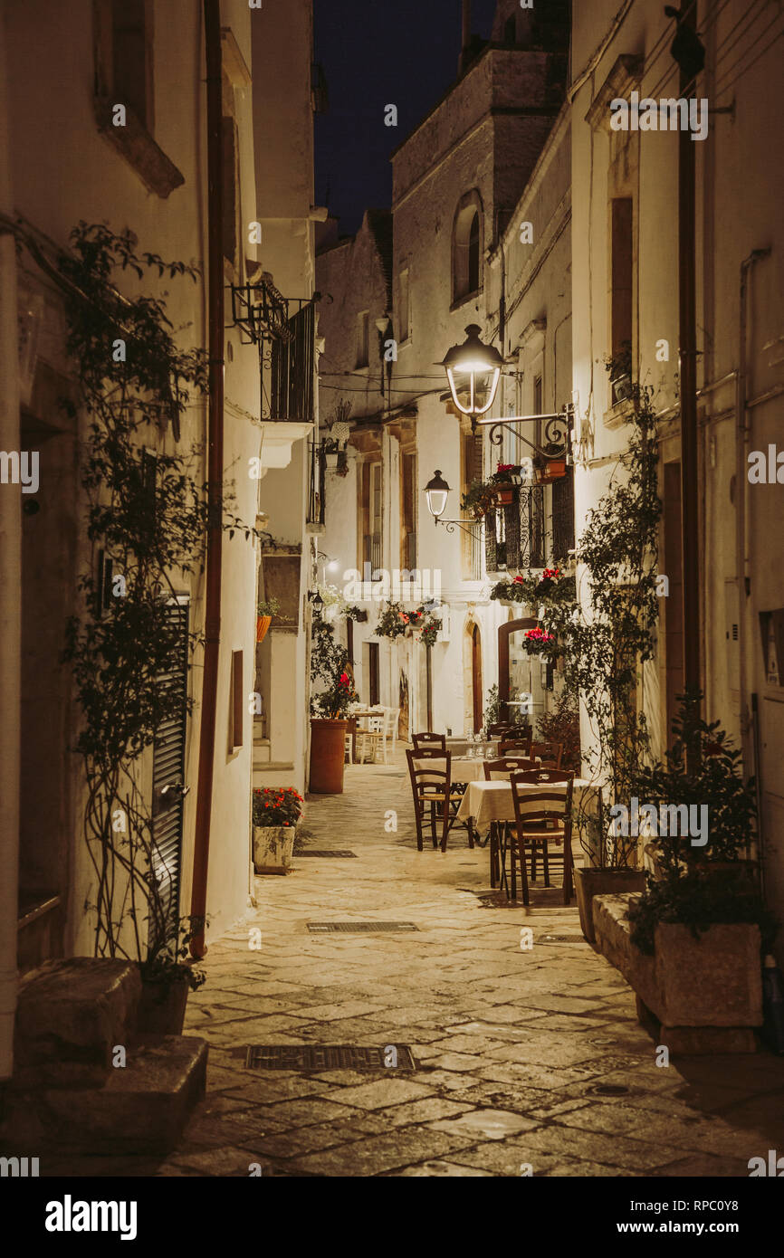 Rue blanche étroite et tables de restaurant dans la région de Locorotondo, région Puglia, Italie Banque D'Images