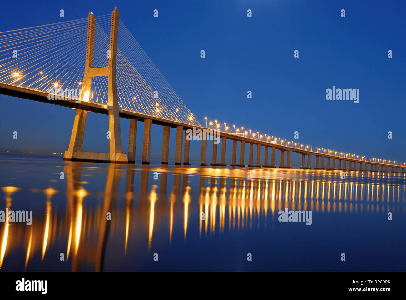 Pont en acier élégante de nuit passant kilomètres sur l'eau de la rivière grand calme Banque D'Images