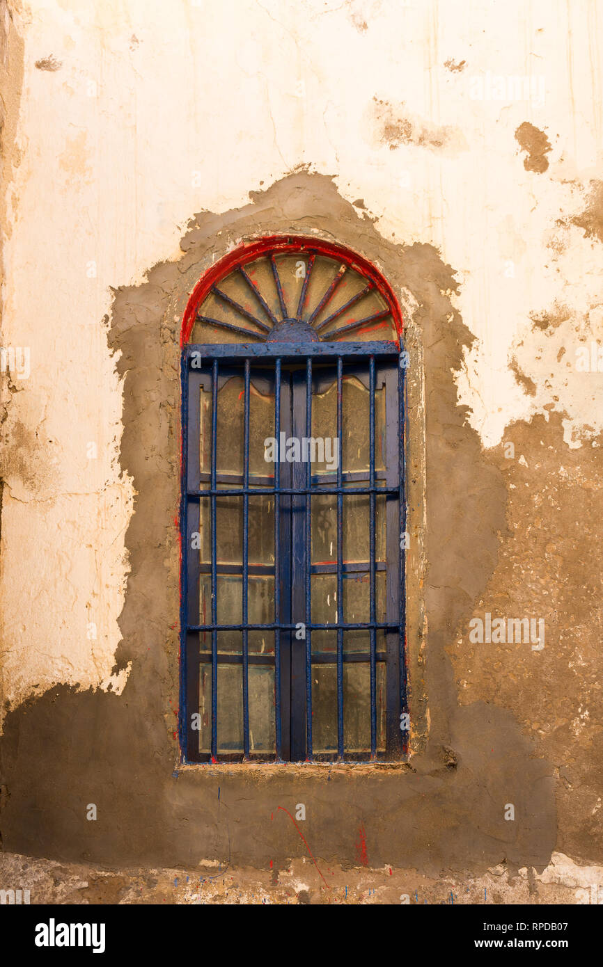 Mur d'une vieille maison avec pela peinture de la façade. Passage de la fenêtre rouge, bleu de râper. Rue de Safi, Maroc. Banque D'Images