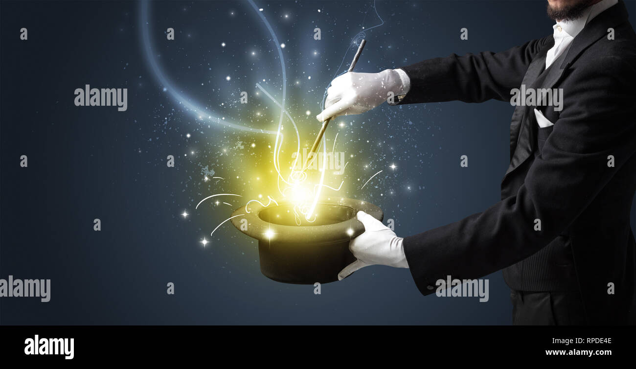 Magicien part évoquer avec la lumière d'une baguette cylindre noir Banque D'Images