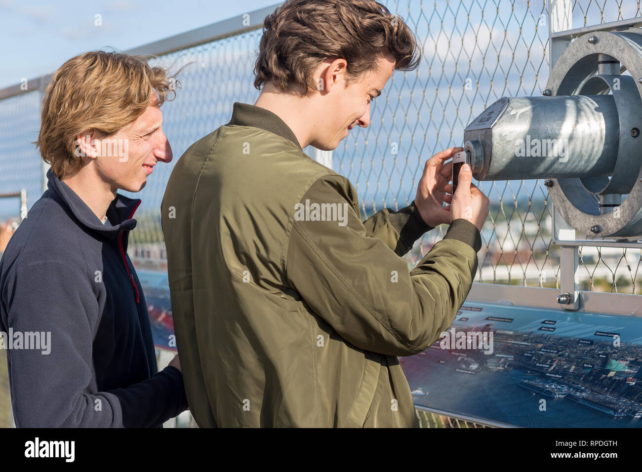 Jeune homme en prenant une photo avec son téléphone mobile via la longue-vue sur le toit de l'Adam Lookout Point de vue avec un ami à regarder Banque D'Images