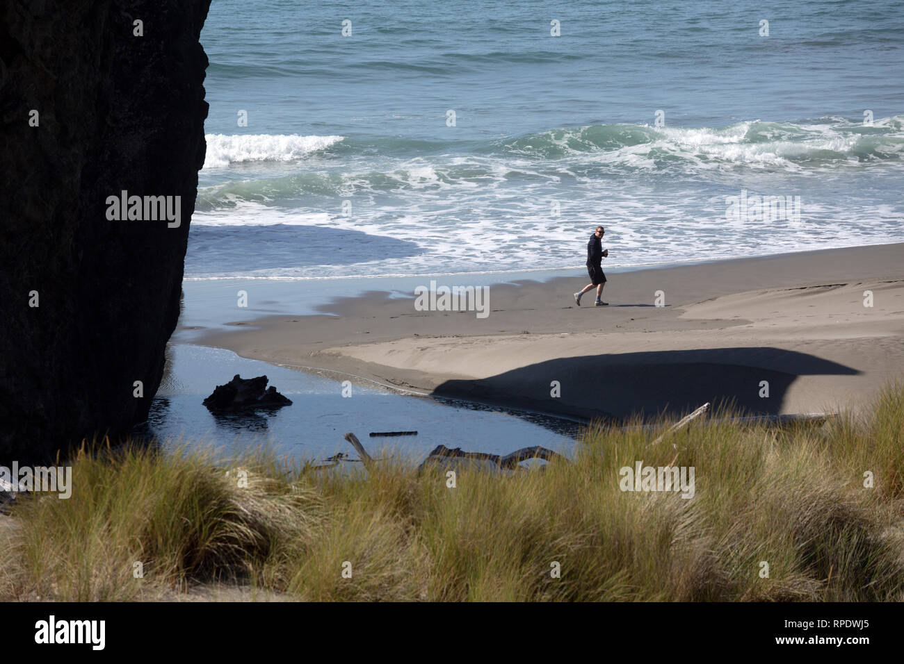 Un solitaire beachcomber marche sur la rive de l'océan Pacifique au large de la route US 101 (l'Oregon Coast Highway), juste au-dessus de la rivière de l'Oregon, au pistolet, l'Amérique Banque D'Images